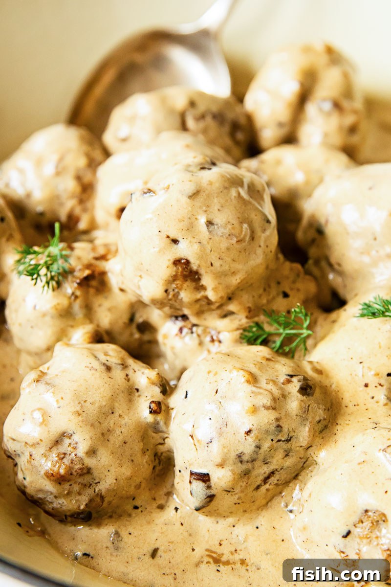 Close up showing the creamy sauce covering perfectly cooked Swedish meatballs in a pan.