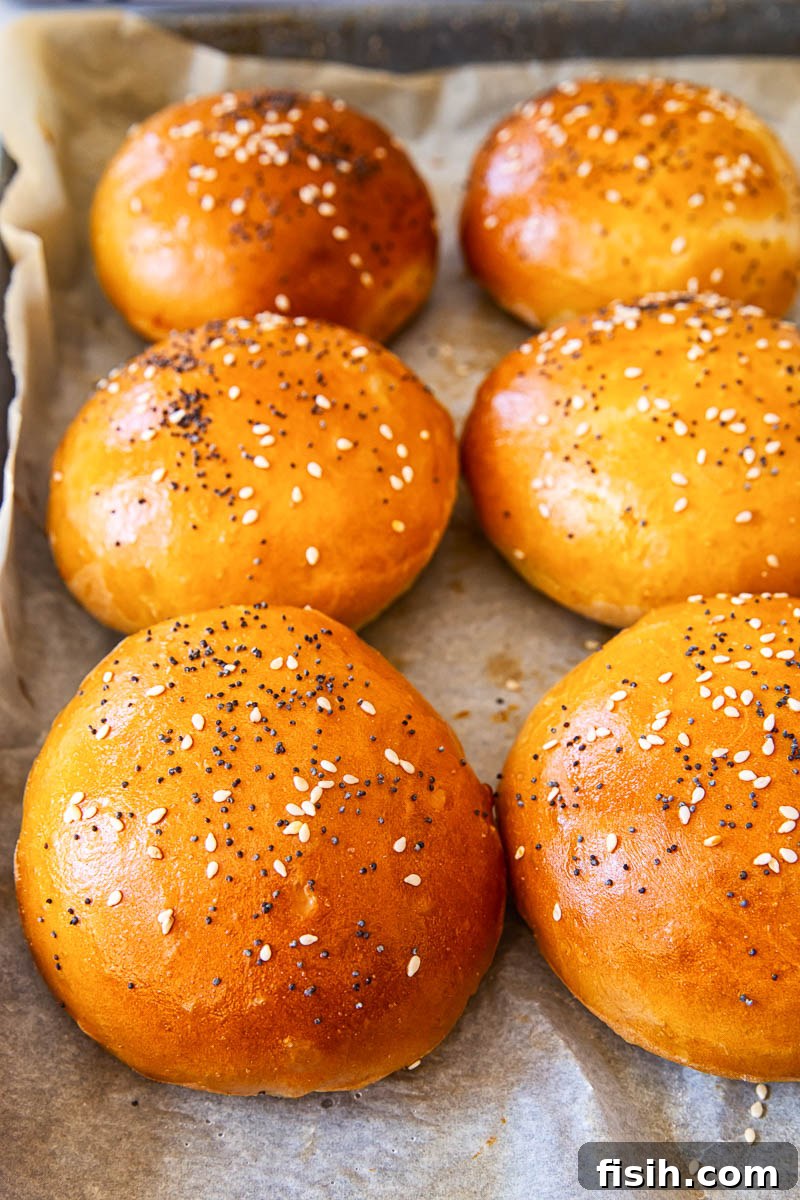 Six perfectly golden, freshly baked burger buns cooling on a wire rack.