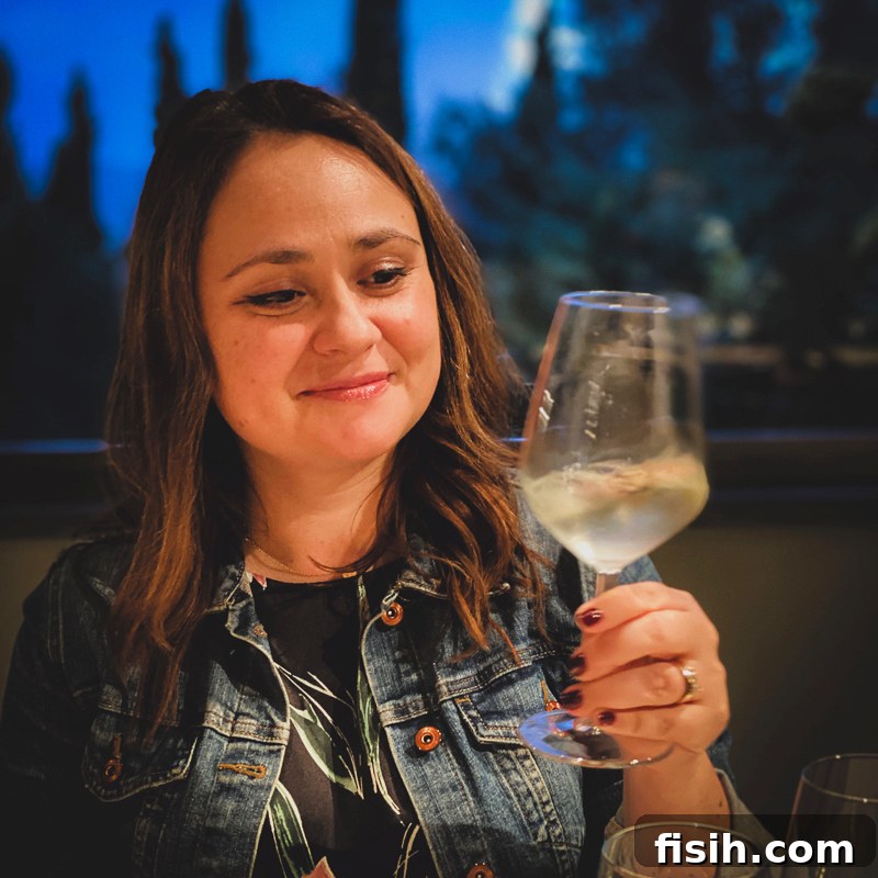 A woman elegantly holding a glass of crisp white wine, enjoying a tasting experience in a sunlit vineyard setting, ready to savor the local flavors.