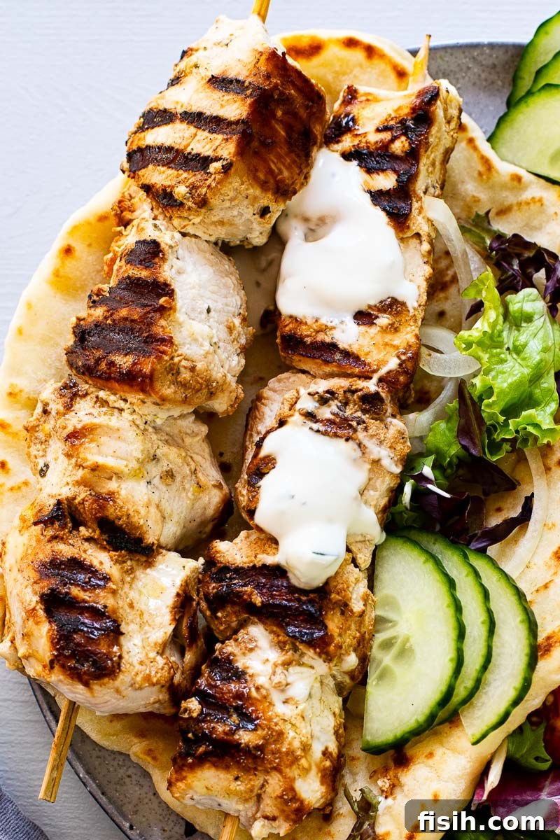 two chicken skewers on top of flatbread drizzled with yogurt