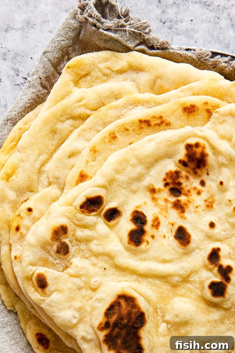 Stacked homemade flatbreads resting on a grey cloth napkin, highlighting their soft and fluffy texture.