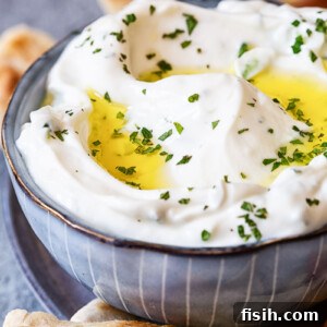 Authentic Greek Tzatziki Recipe 6 Tzatziki sauce in blue bowl, pita bread around it.