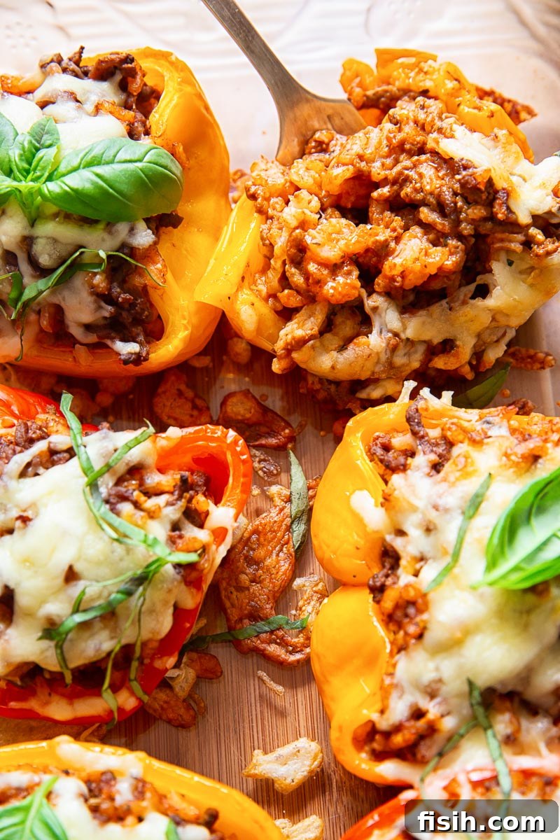 Close-up of a halved stuffed bell pepper, showcasing the rich, cheesy beef risotto filling, ready for baking.