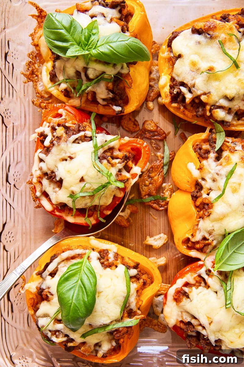Overhead shot of two beautifully stuffed red and yellow bell peppers, garnished with fresh herbs, in a baking dish.
