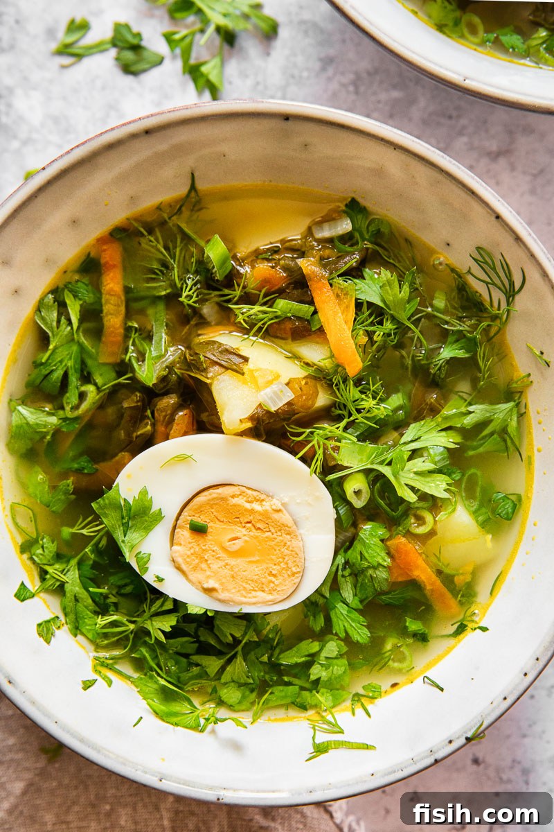 green borscht topped with parsley and dill and a hard boiled egg half