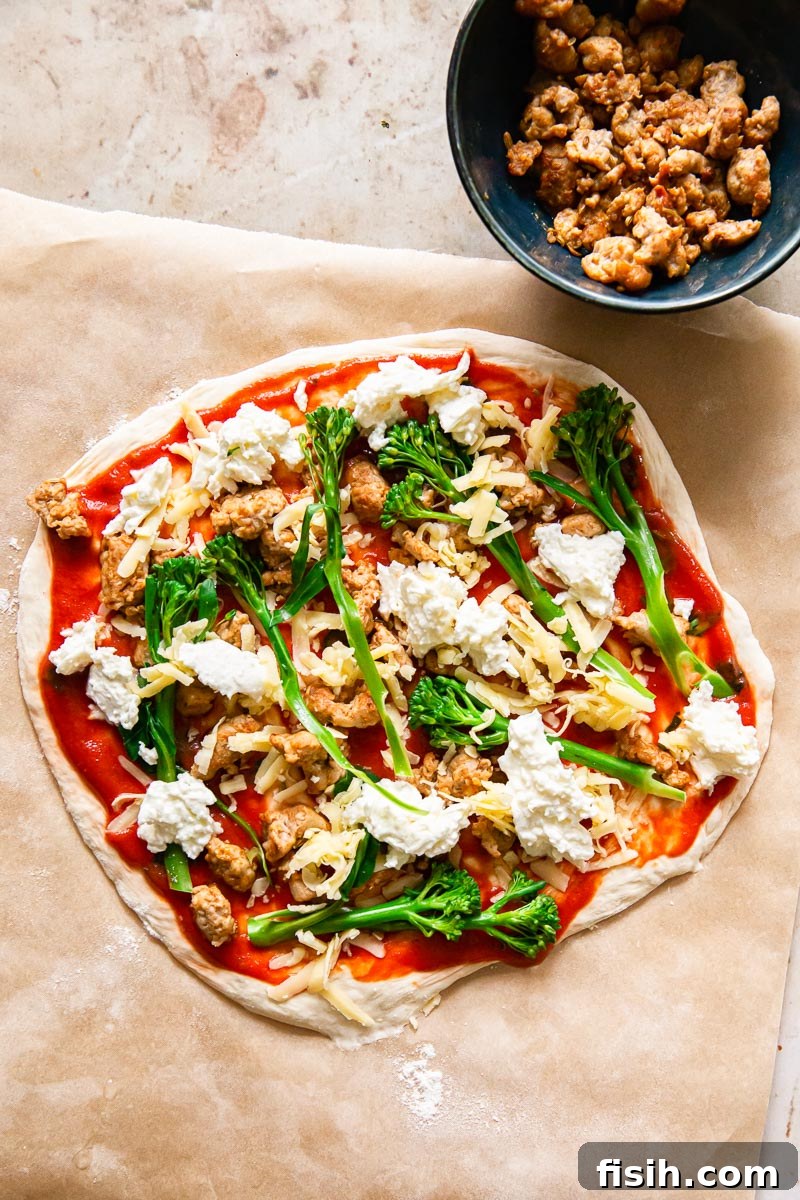 Unbaked pizza crust topped with spicy sausage, tenderstem broccoli, and fresh mozzarella