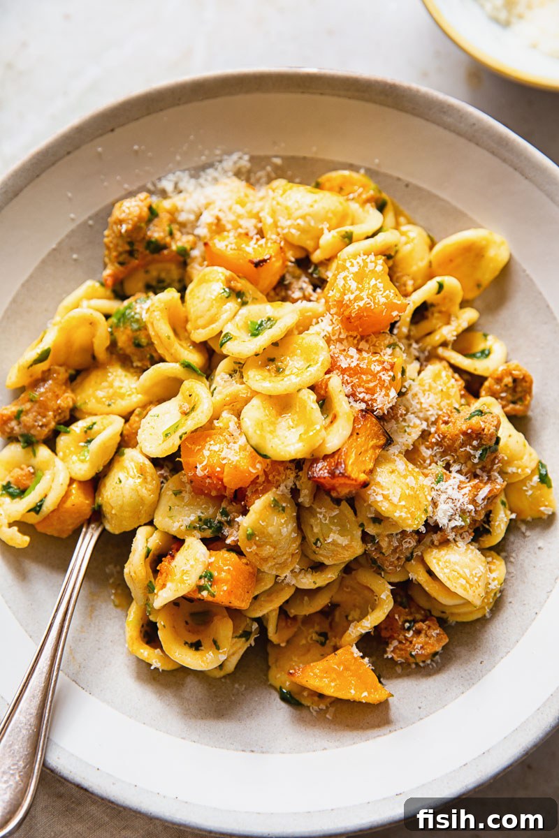 Delicious orecchiette pasta with spicy chorizo, spinach, and roasted butternut squash in a creamy Parmesan sauce, served in a bowl.