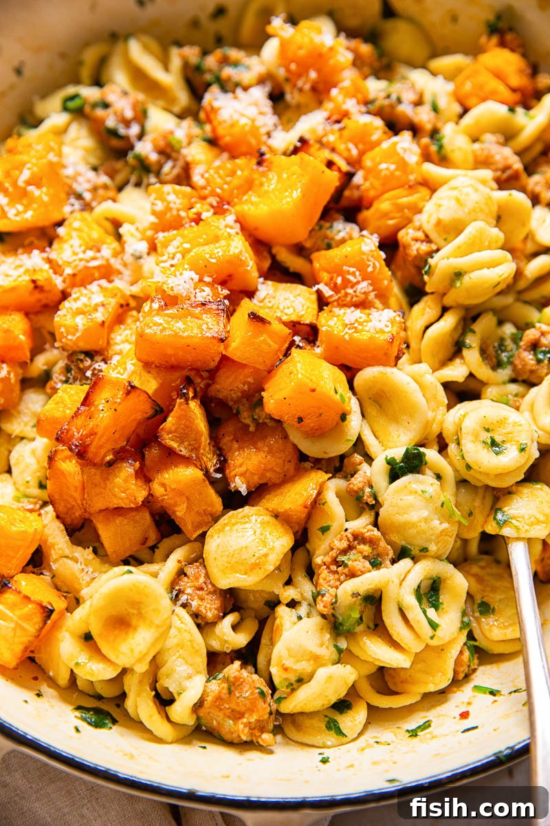 Roasted butternut squash on top of orecchiette pasta with chorizo sausage and spinach, ready to be served.