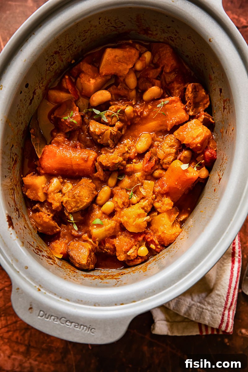 The savory pork and vegetable stew simmering gently inside a slow cooker, promising rich flavors and tender textures.