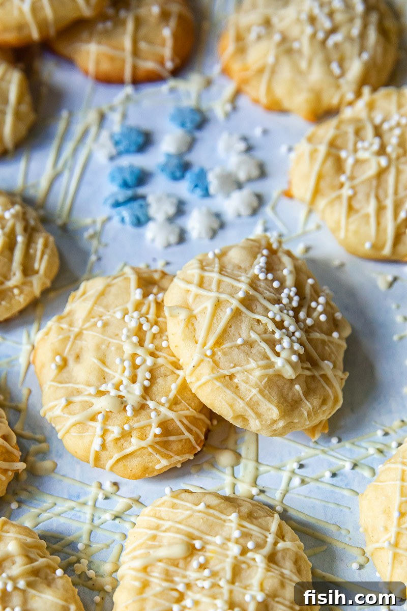 Close-up of lemon ricotta cookies adorned with white chocolate drizzle on a serene light blue background, highlighting their delicate texture.