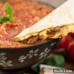 Quesadilla being dipped in salsa, showcasing the fresh, vibrant flavors.