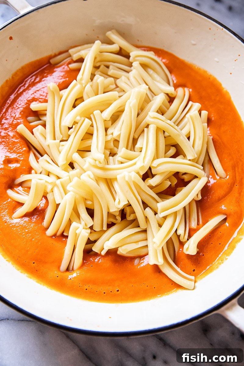 Velvety Vodka Pasta Sauce 3 Fresh pasta on a white pan, ready to be coated with vodka sauce.