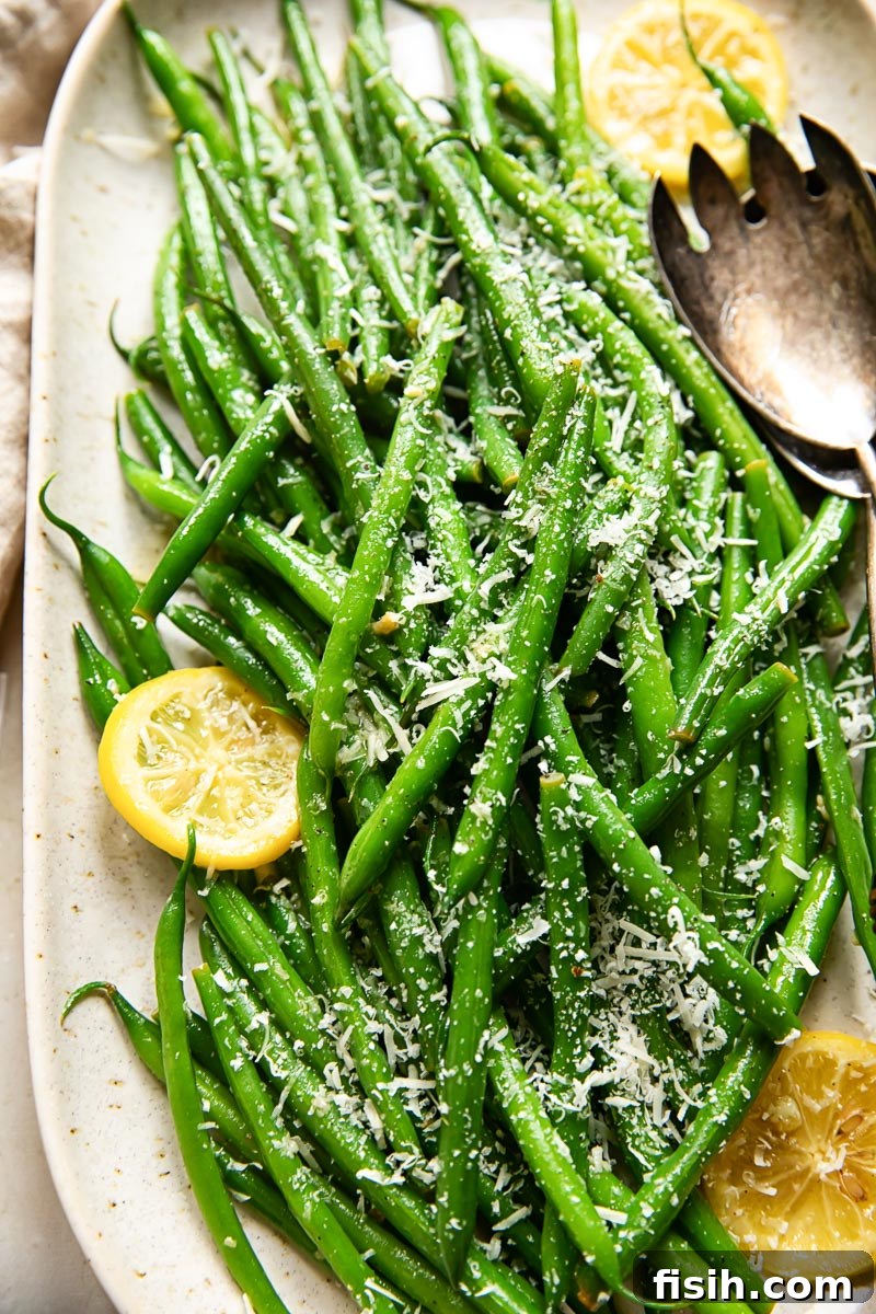 Bright Lemon-Garlic Parmesan Green Beans 2 Green beans topped with grated Parmesan and fresh lemon slices on an elegant serving platter, showcasing a vibrant and fresh side dish.