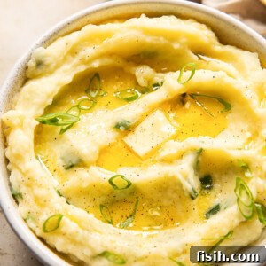 mashed potatoes topped with melted butter and sliced green onions in a bowl