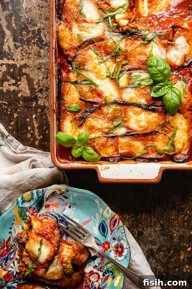 Guilt-Free Eggplant Parmigiana 3 A serving of authentic Melanzane alla Parmigiana, fresh from the oven, resting in a baking dish with a portion neatly plated on a vibrant blue dish, garnished with basil.