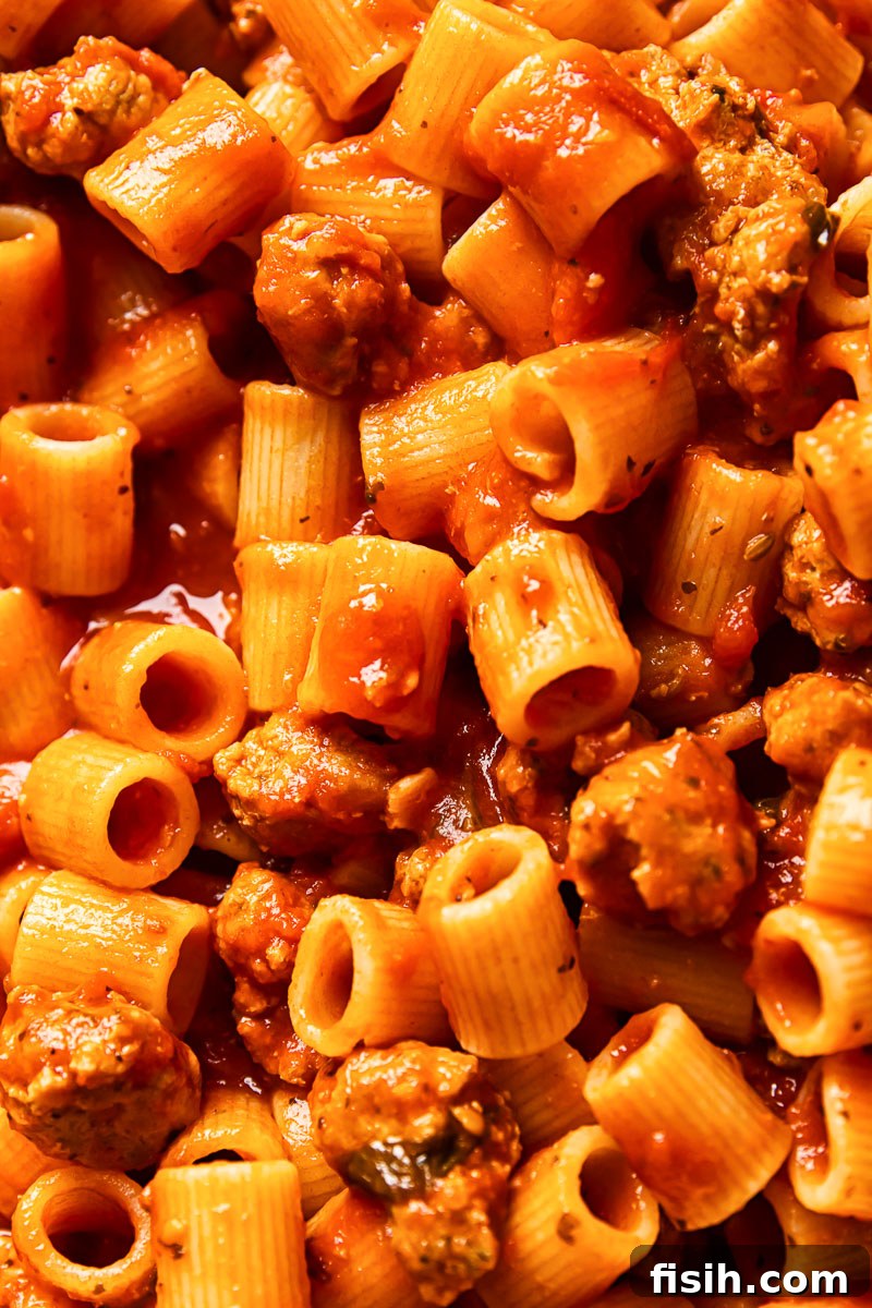 Zesty Sausage Pasta with Creamy Ricotta 6 Close-up shot of a serving of spicy sausage pasta with visible chunks of sausage, sauce, and creamy ricotta.