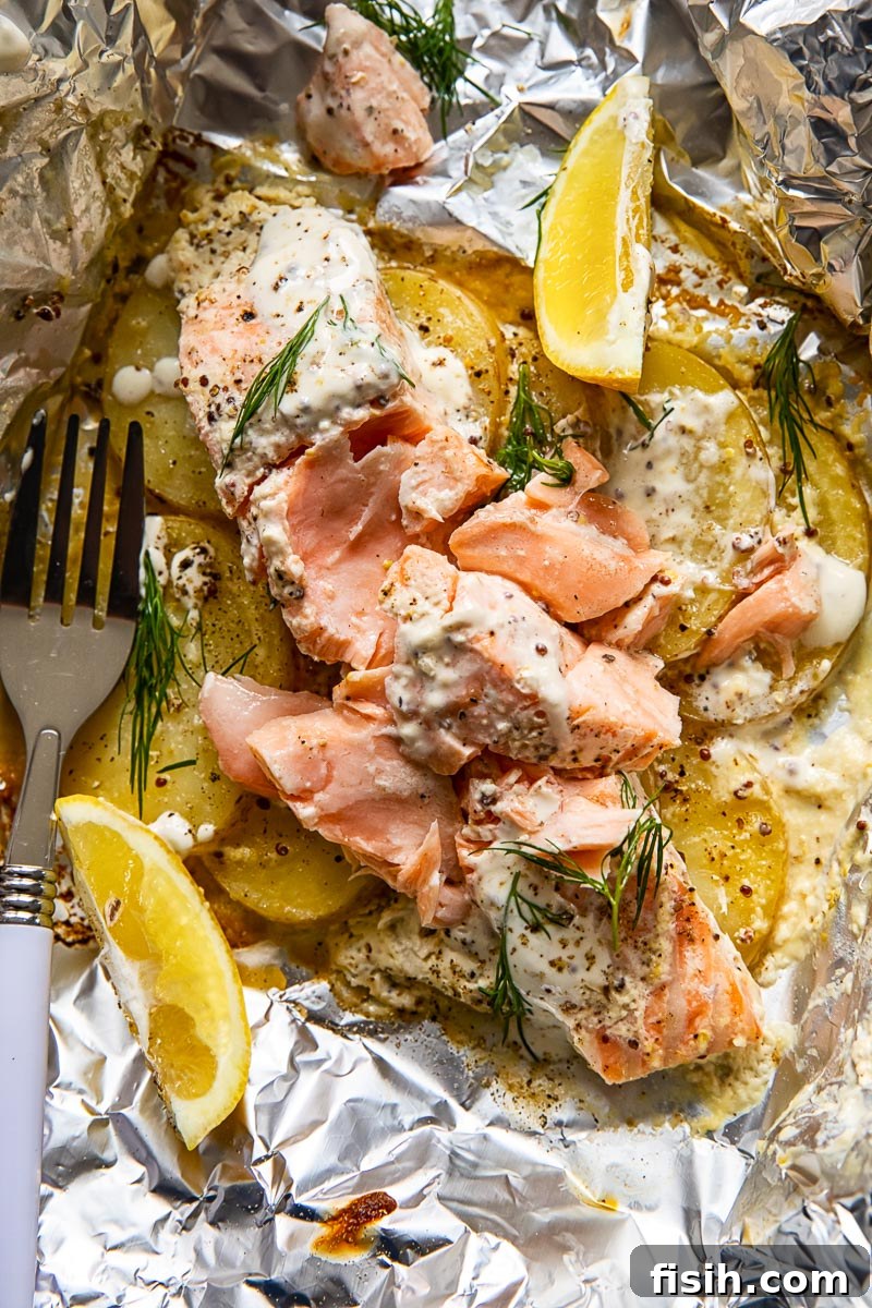 Campfire Salmon and Potato Foil Packs 5 flaked salmon on top of potato slices in foil, garnished with lemon wedges and fresh dill