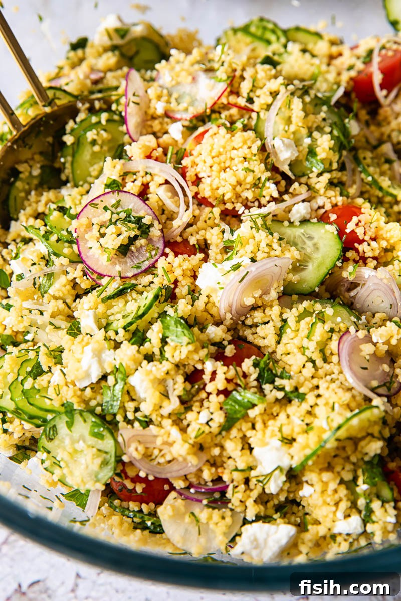 Close-up detailed view of a vibrant couscous salad, showcasing the individual grains, fresh herbs, and colorful vegetables, perfect for a sunny day.