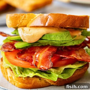 Close up of BLT sandwich with avocado and sauce spilling over