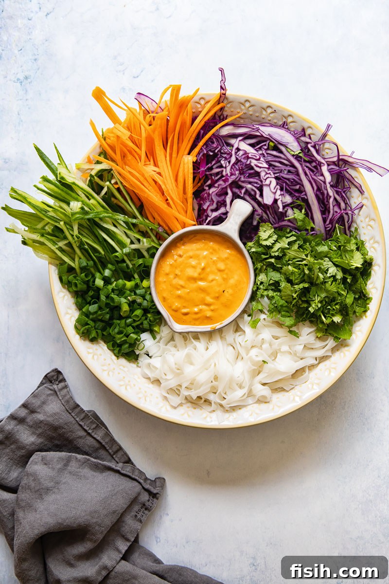 A bowl filled with the colorful components of the rice noodle salad, including thinly sliced vegetables and cooked noodles, ready to be dressed.