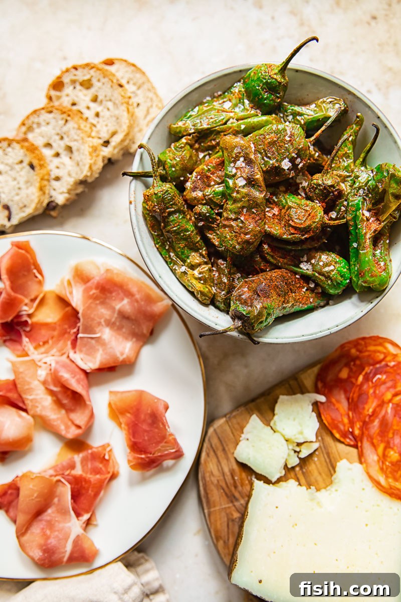 top down view of Padron peppers, Serrano ham, chorizo, and cheese on a wooden board, perfect for a tapas party