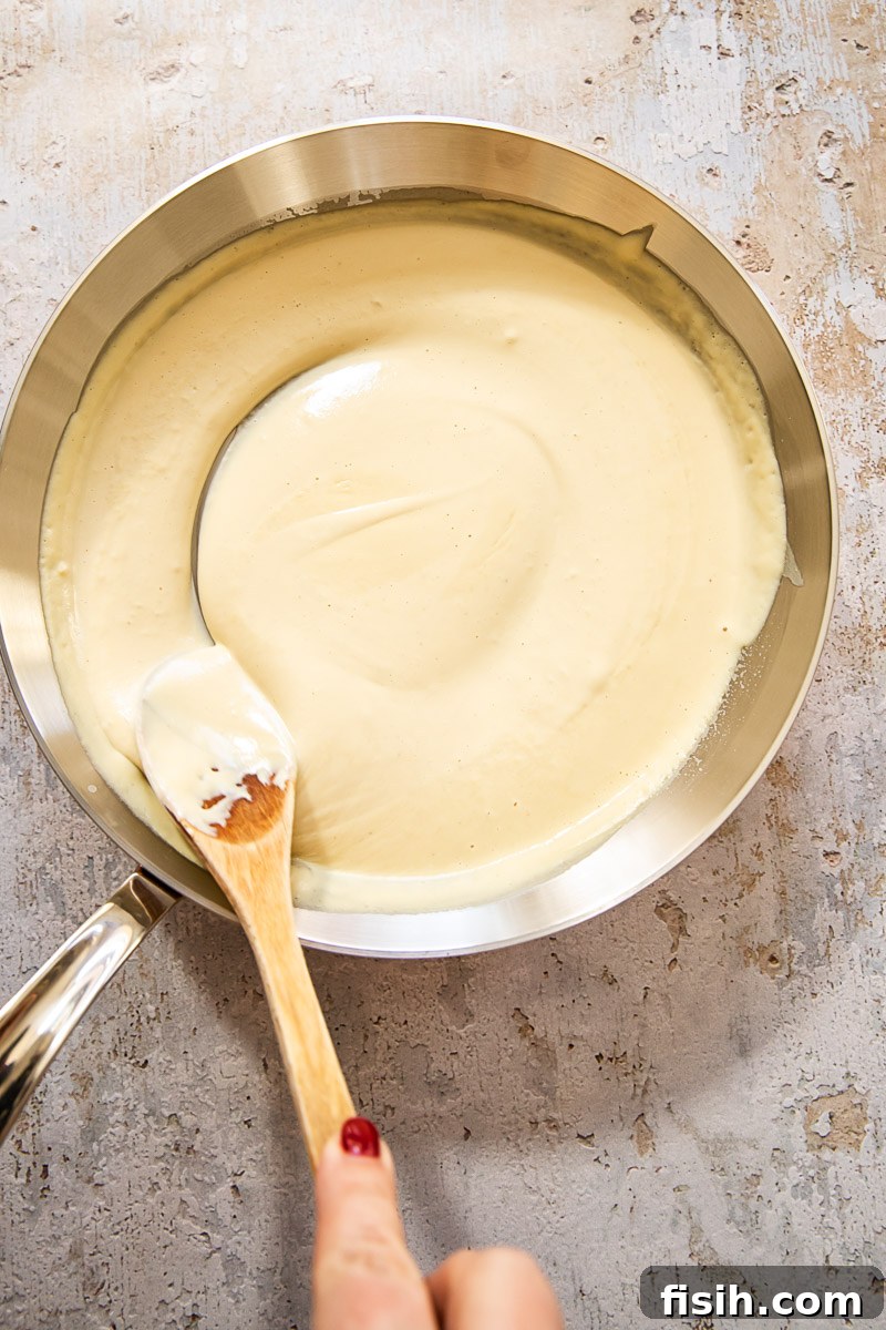A golden, creamy cheese sauce gently simmering in a pan, ready to be tossed with hot pasta.