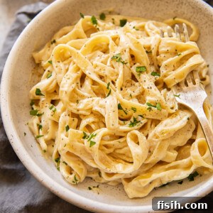 Top down view of a finished plate of Fettuccine Alfredo, garnished and ready to be served.