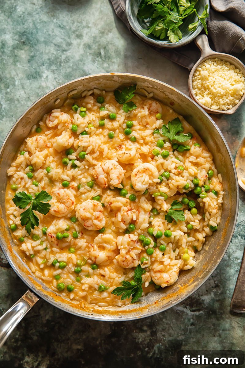 top down view of prawn risotto in a pan, two little bowls with Parmesan and parsley