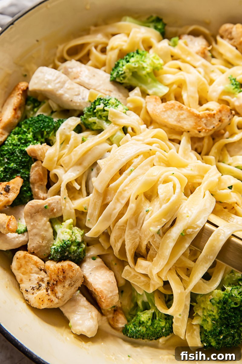 fettuccine in a creamy sauce with chicken and broccoli in a pan, ready to be served
