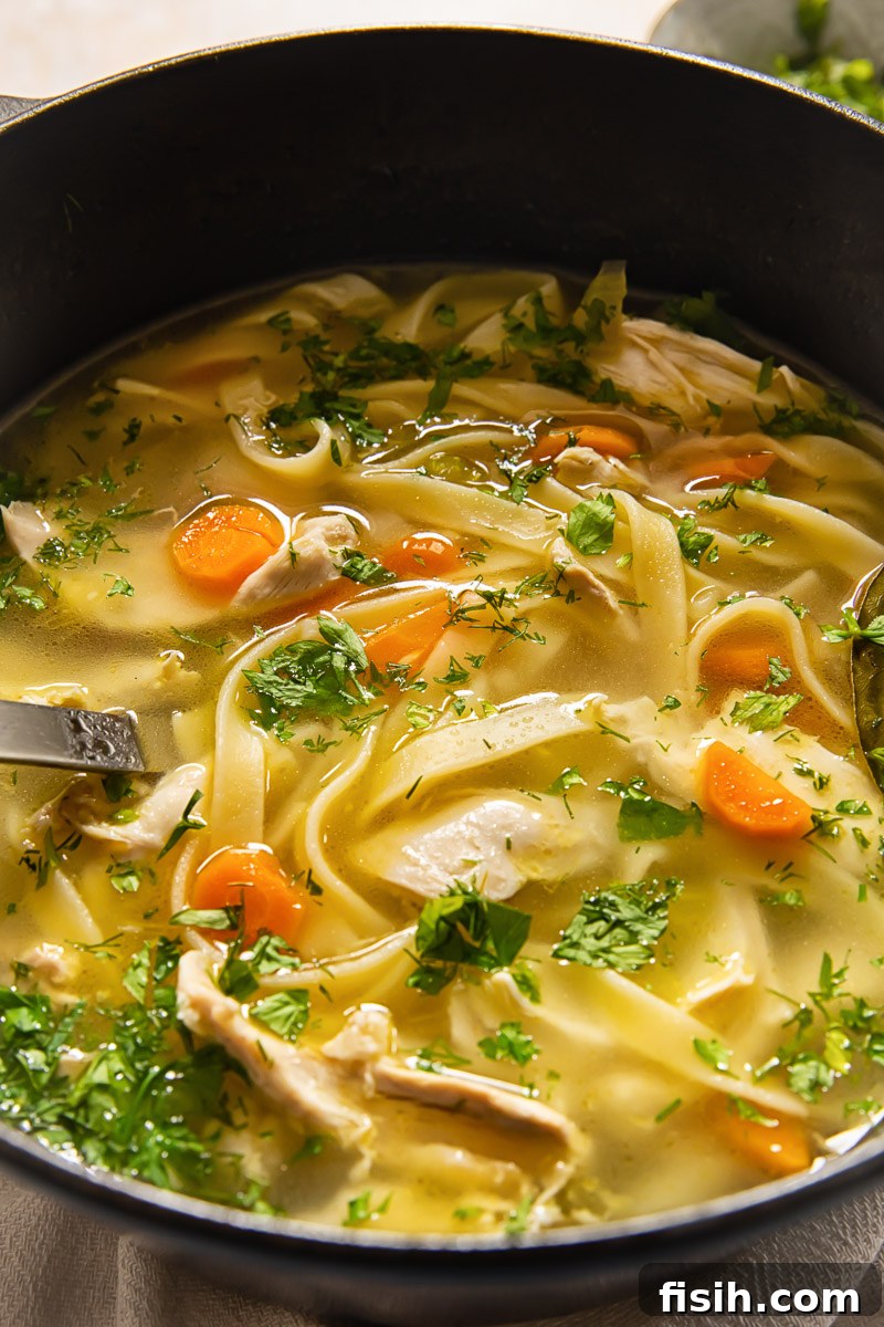 Grandma's Comforting Chicken Noodle 6 soup sprinkled with fresh herbs in a pot
