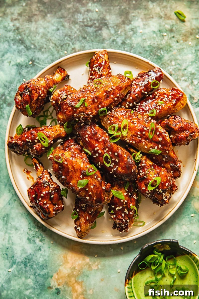 Overhead view of a serving of sticky Asian Air Fryer Chicken Wings garnished with sesame seeds and green onions