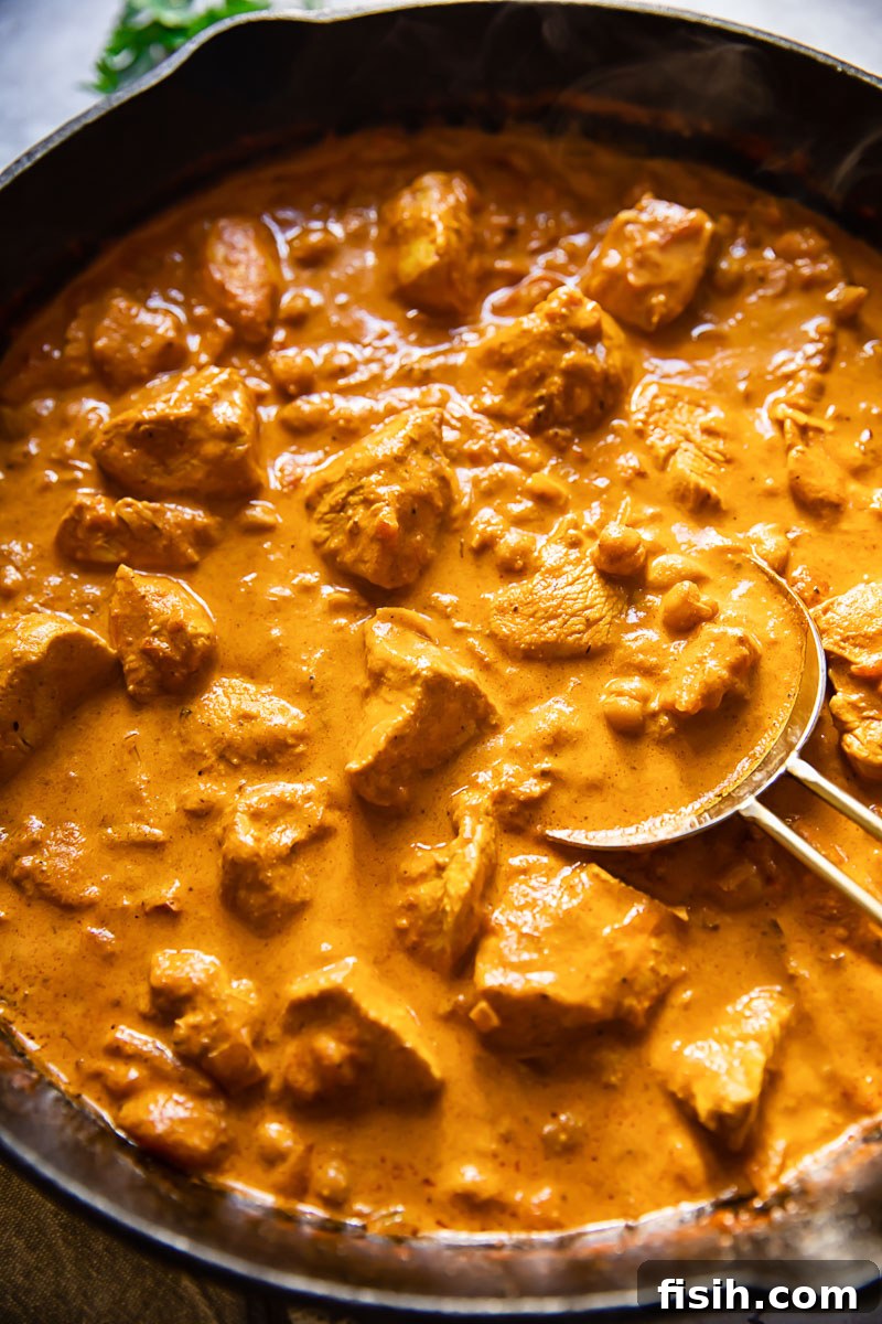 Rich and Creamy Chicken Tikka Masala 4 Close-up shot of Chicken Tikka Masala with chickpeas simmering in a black pan, showcasing its rich texture and color.