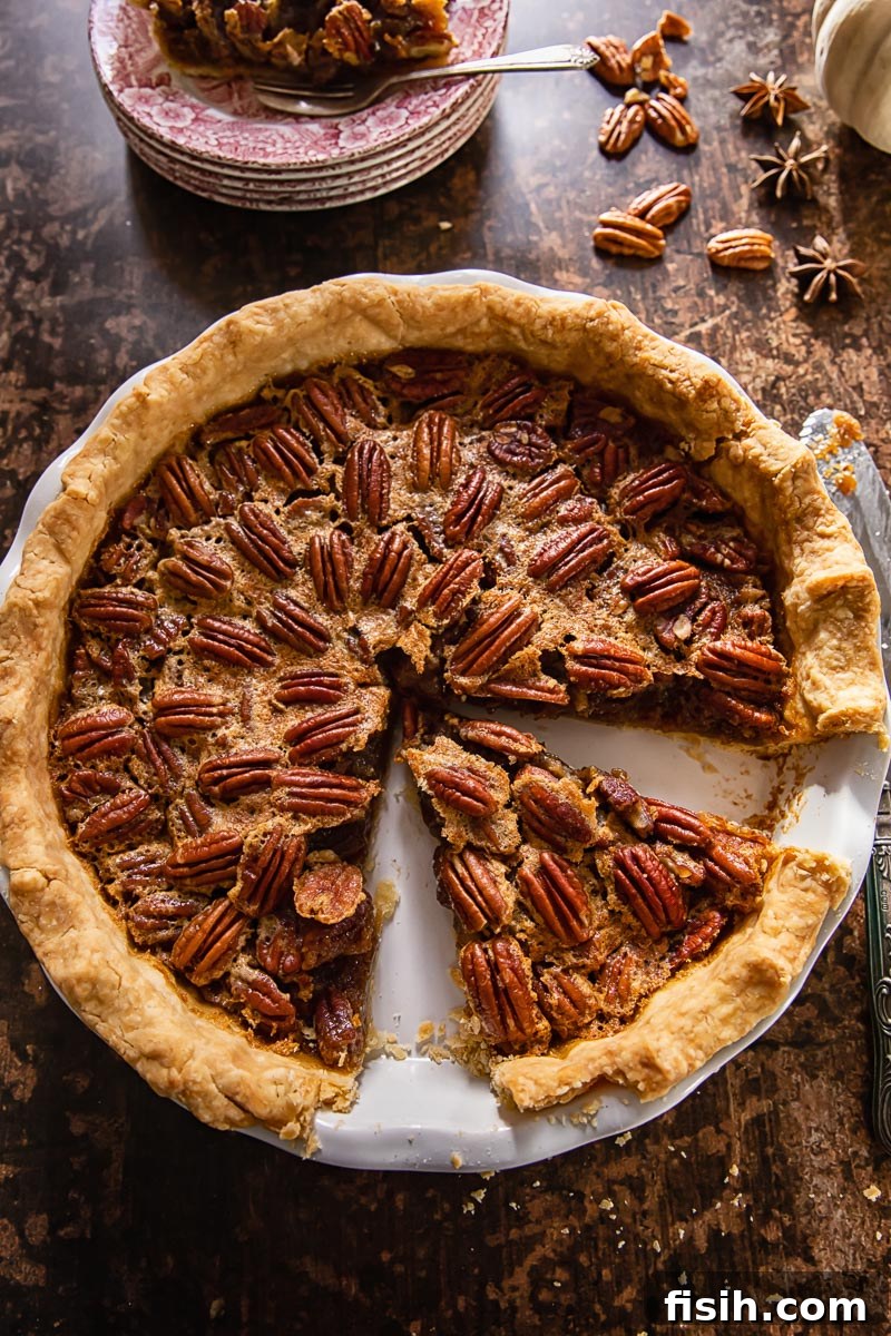 Spiked Maple Pecan Perfection 3 An overhead view of a whole Maple Bourbon Pecan Pie with one slice removed, revealing its delicious, nut-filled interior.