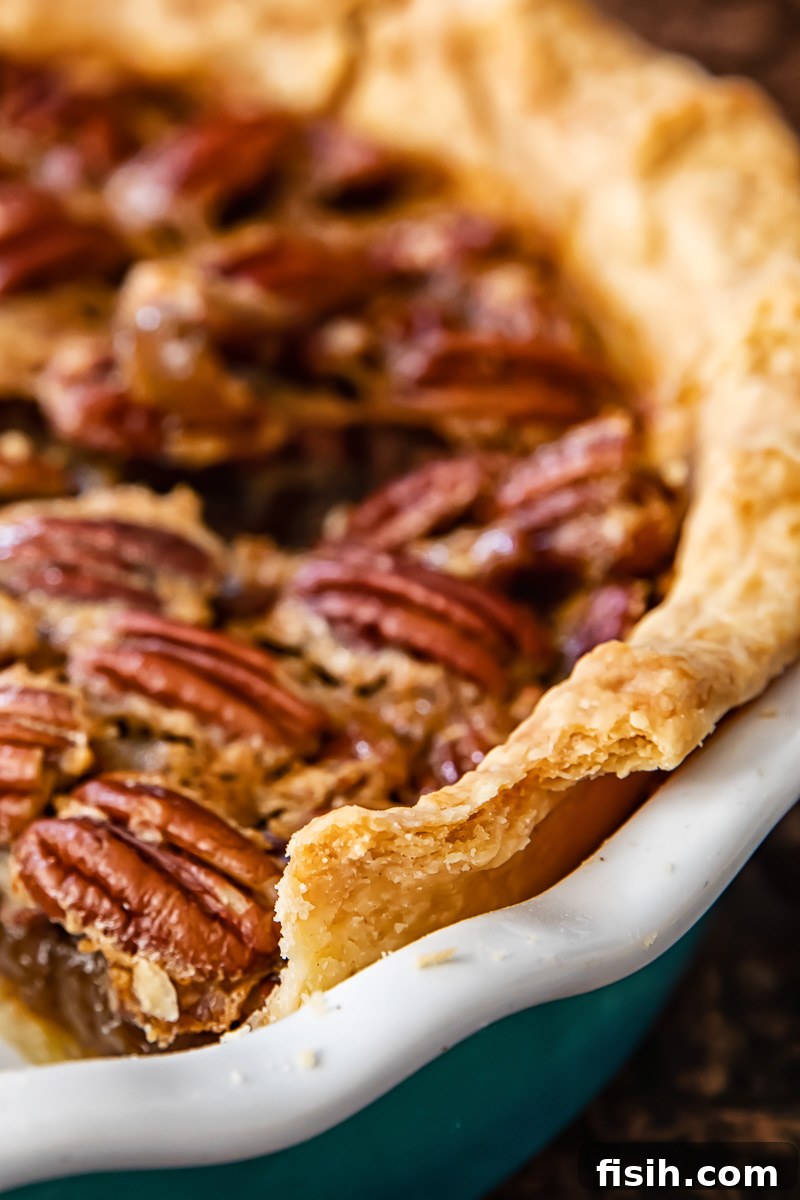 Spiked Maple Pecan Perfection 4 A close-up shot of a baked pie crust edge, highlighting its golden-brown color and distinct flaky layers.