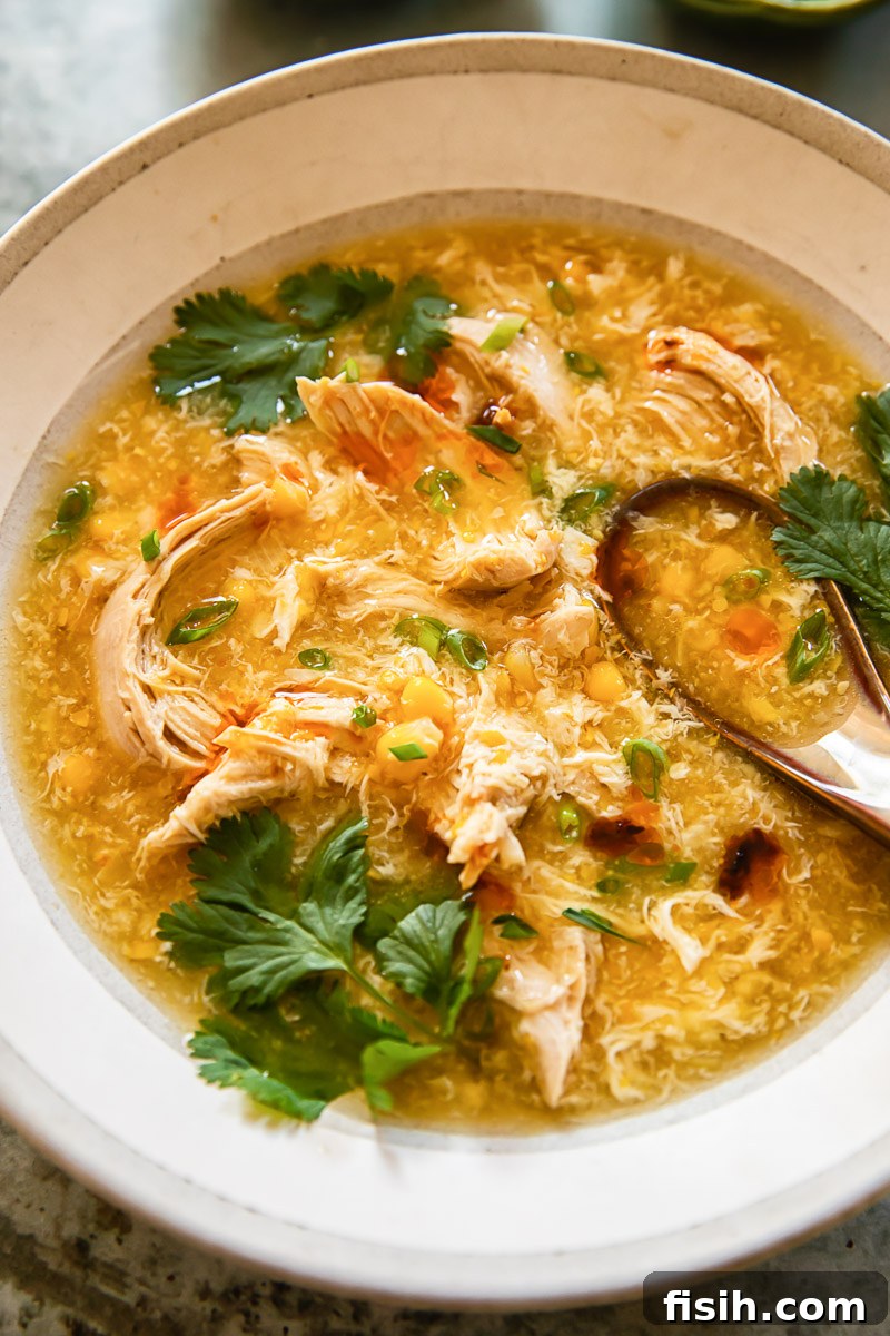 A steaming bowl of chicken and sweetcorn soup, garnished with vibrant fresh coriander leaves, invitingly placed on a rustic wooden table.