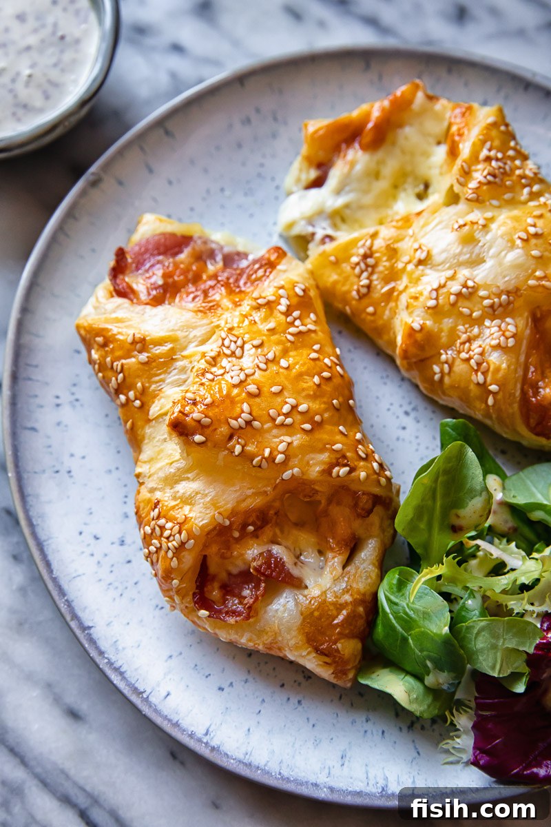 Smoky Bacon & Cheese Pastry 2 Golden brown bacon and cheese turnovers artfully arranged on a plate, garnished with fresh salad greens, highlighting their flaky texture.