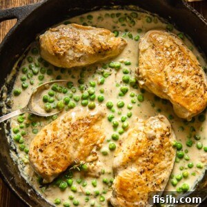 Velvety Chicken and Green Peas 5 top down view of cast iron pan with chicken breasts and green peas in a creamy sauce
