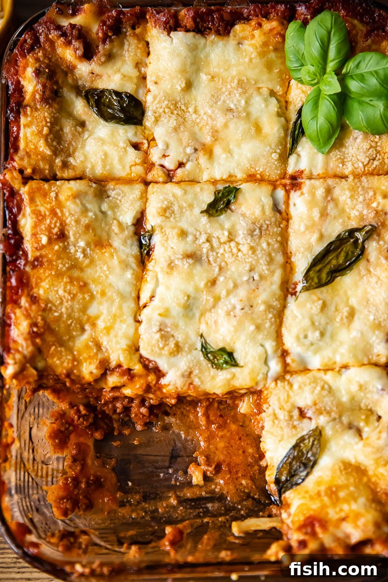 Top down view of a beautifully baked classic lasagne in a pan, perfectly cut into squares, ready to serve, showcasing a golden-brown top and distinct layers.