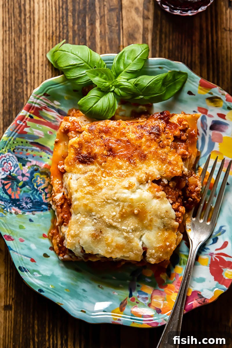 A perfectly portioned slice of classic lasagne, showcasing its distinct layers of pasta, rich Bolognese, and creamy Béchamel, resting on a blue plate, ready to be enjoyed.