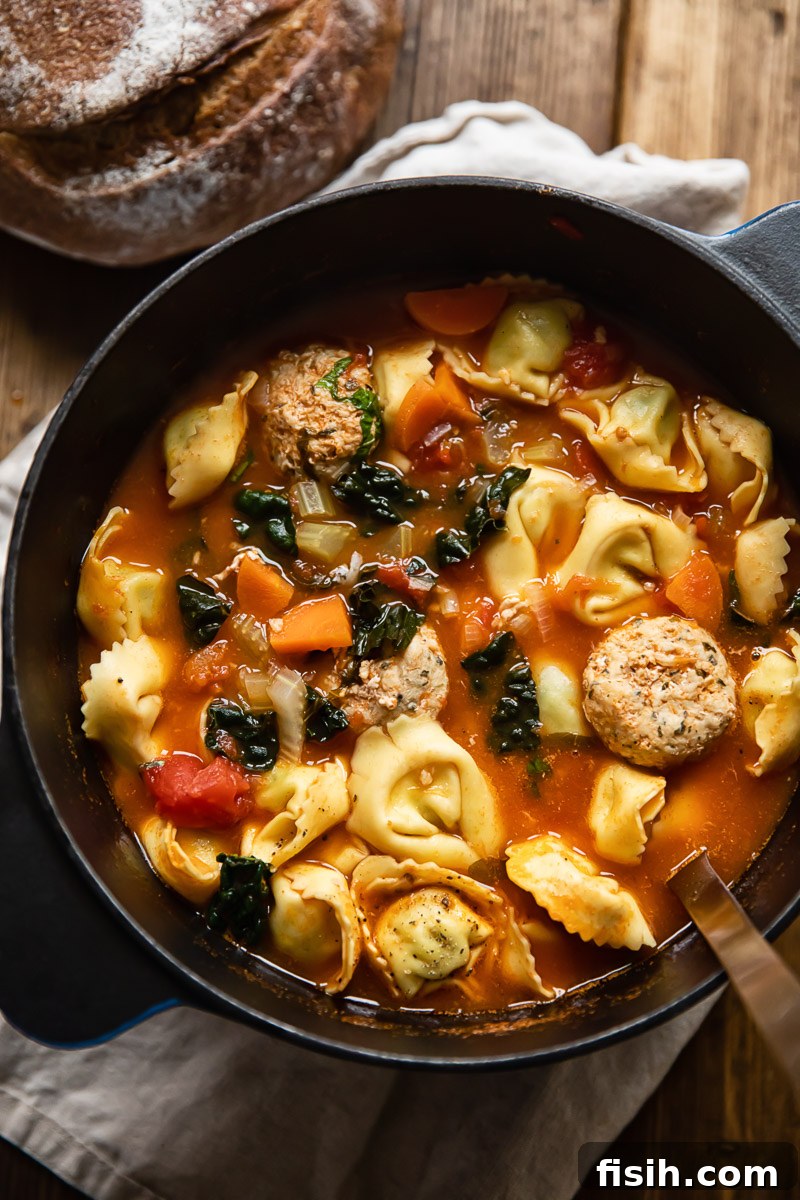 A close-up shot of hearty meatball tortellini soup with vibrant kale, showcasing the rich broth and diverse ingredients, ready to be enjoyed.