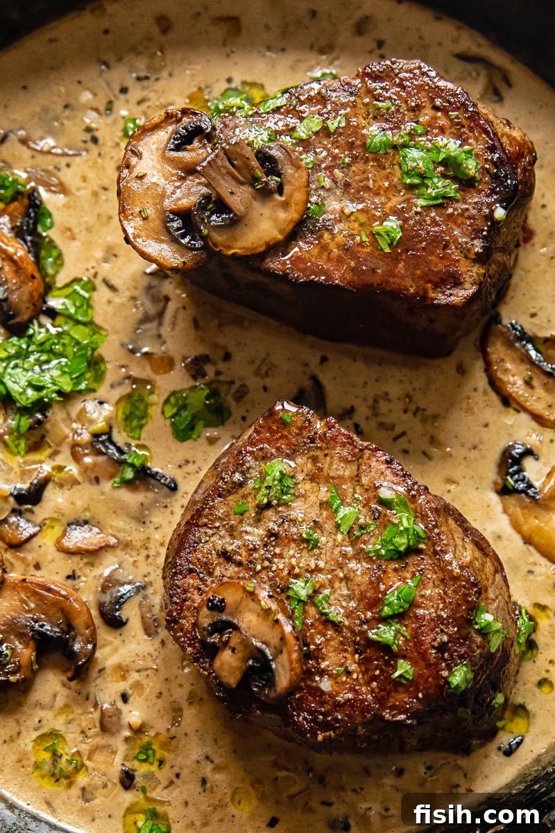 Two exquisitely cooked fillet steaks bathed in a creamy mushroom marsala sauce, ready to serve.