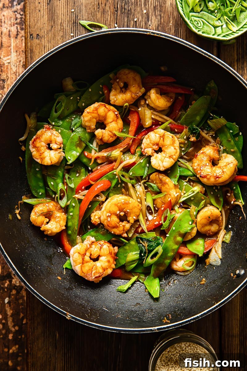 top down view of shrimp stir fried with vibrant vegetables in a wok, ready to be served