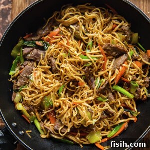 A close-up, top-down view of Asian noodles dish with beef and vegetables in a wok