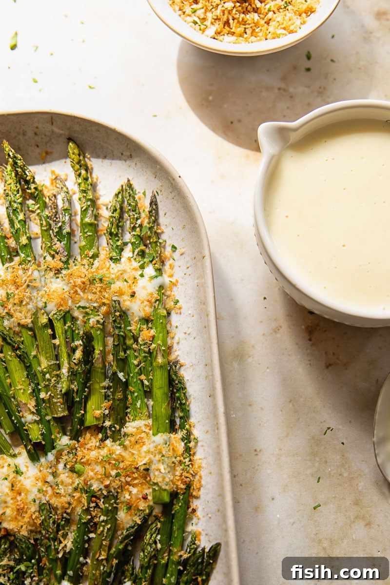 Mornay Asparagus Bake with Toasted Crumbs 4 asparagus with breadcrumbs on a platter and cheese sauce in a bowl