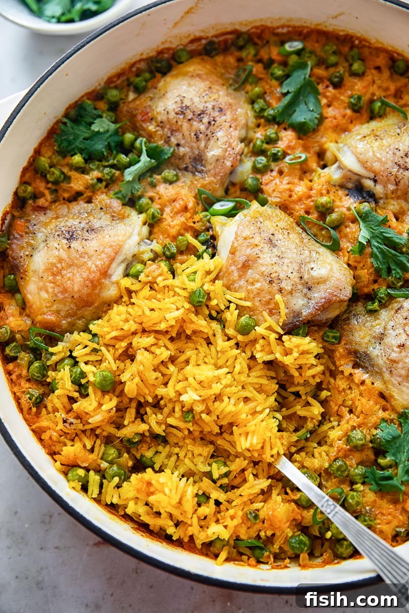 Top-down view of a delicious one-pan chicken thigh and yellow turmeric rice casserole with vibrant green peas, ready to serve.