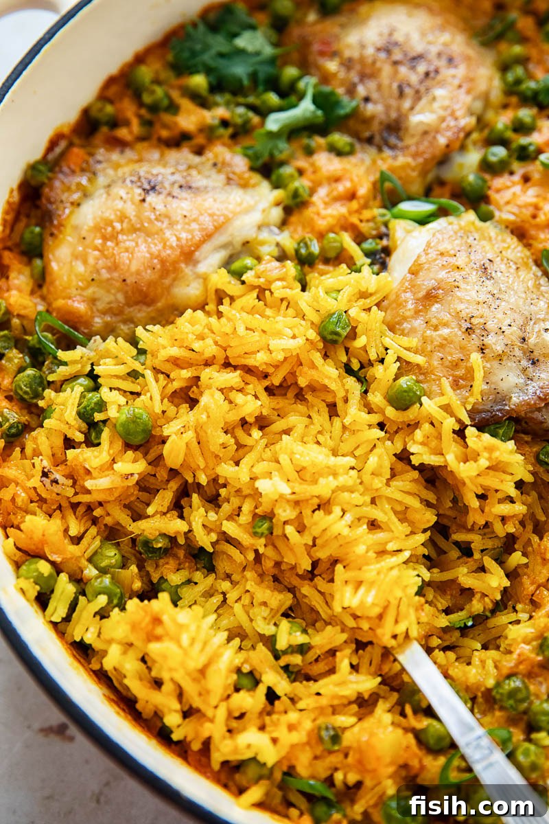 Close-up shot of fluffy yellow Basmati rice with tender chicken cooked to perfection in a cast iron pan.