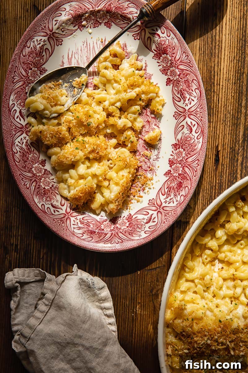 Golden Crusted Mac and Cheese 5 Close-up of baked macaroni and cheese in a casserole dish and a serving on a plate, with a cream napkin for texture.