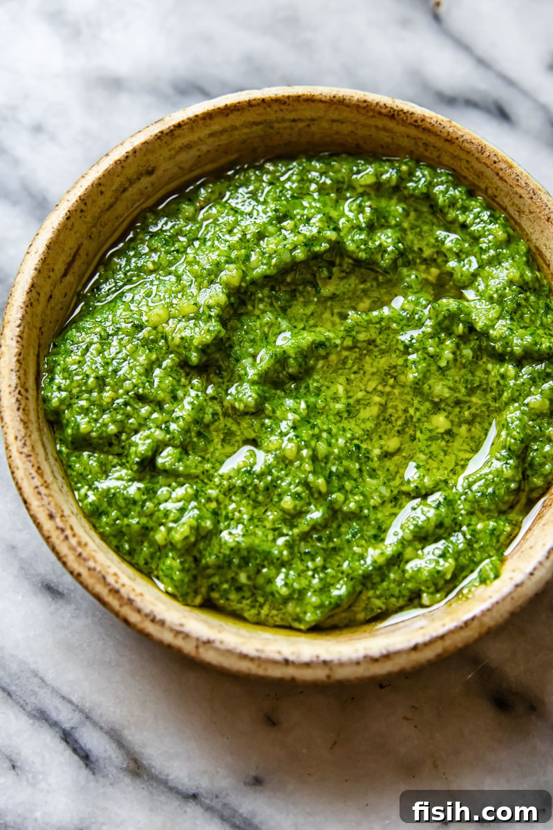 A beige bowl filled with vibrant green basil pesto, ready to be served
