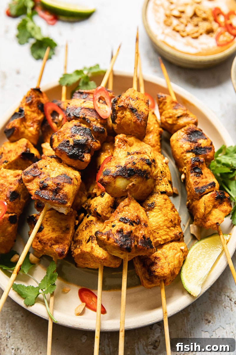 Simple Chicken Satay with Creamy Peanut Sauce 2 Perfectly grilled chicken satay skewers arranged beautifully on a plate, accompanied by a small bowl of creamy peanut dipping sauce, showcasing the dish's irresistible appeal.