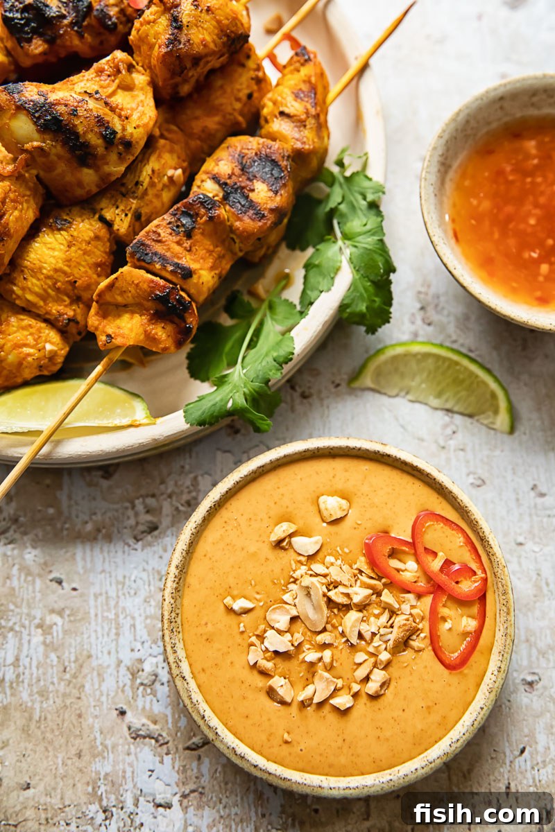 Simple Chicken Satay with Creamy Peanut Sauce 5 An aesthetically pleasing top-down view of chicken satay skewers arranged on a rustic plate, with a small bowl of creamy peanut sauce, fresh cilantro, and lime wedges, ready for serving.